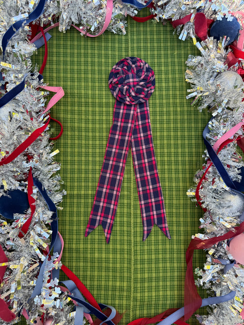 Plaid ribbon on a green checkered fabric with festive tinsel border