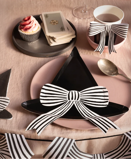 Table setting with black and white striped bow decorations on plates and a cup.