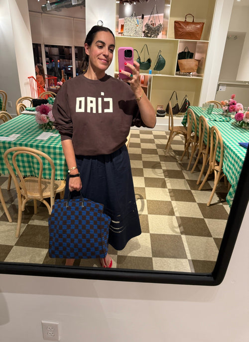 Person taking a mirror selfie in a dining area with a checkered floor.