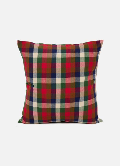 A square throw pillow featuring a classic plaid pattern in red, green, navy blue, beige, and brown, set against a plain light gray background.
