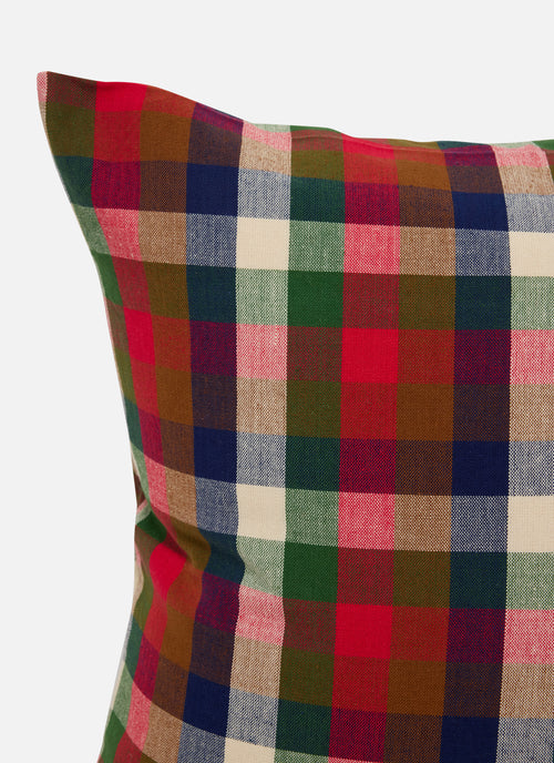 A close-up of a plaid throw pillow featuring a multi-colored tartan pattern with red, green, navy, beige, and brown stripes on a light gray background.