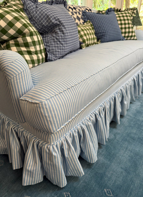 Gray striped sofa with decorative pillows on a blue carpet
