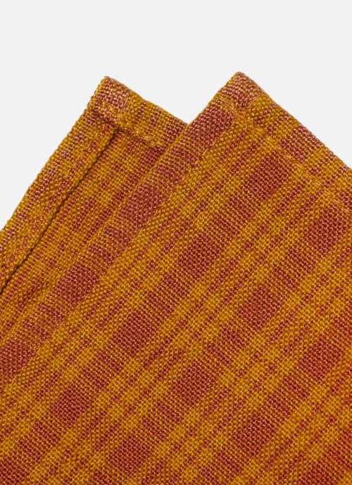 Close-up of a textured fabric with a checkered pattern in orange  on a white background.