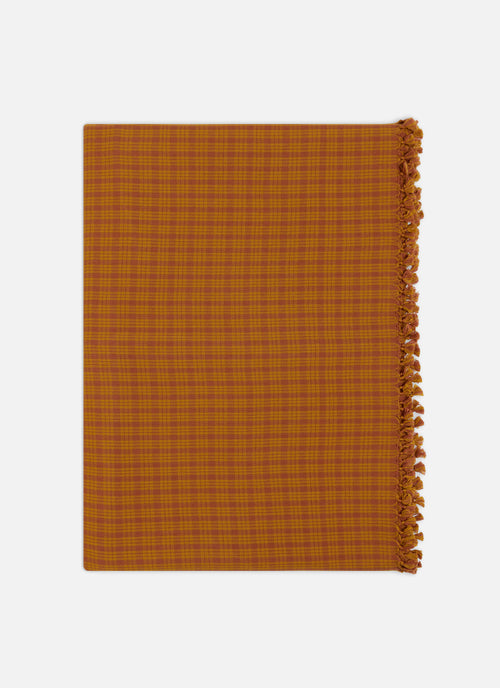 Orange woven tablecloth with tassels on a white background