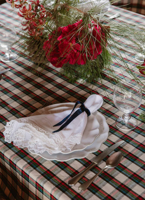 Decorative table setting with red flowers, greenery, and a checkered tablecloth.