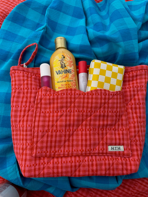 Red checkered pouch with Vahine product and other items on a blue checkered background