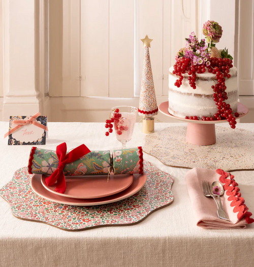 Decorative Christmas table setting with a cake, crackers, and place settings.