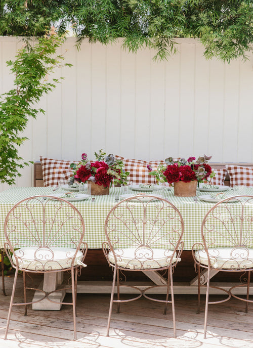 Outdoor dining setup with a table, chairs, and floral centerpieces.