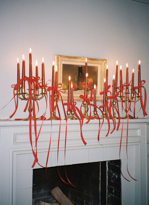 Decorative candelabra with red ribbons on a fireplace mantel.