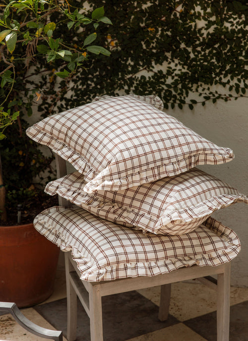 Stack of plaid cushions on a stool with a plant in the background