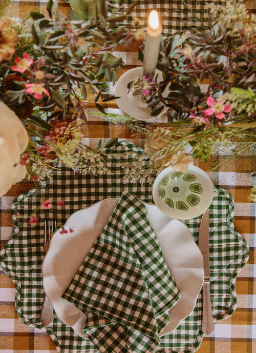 Decorative table setting with checkered tablecloth, plates, and floral arrangements.