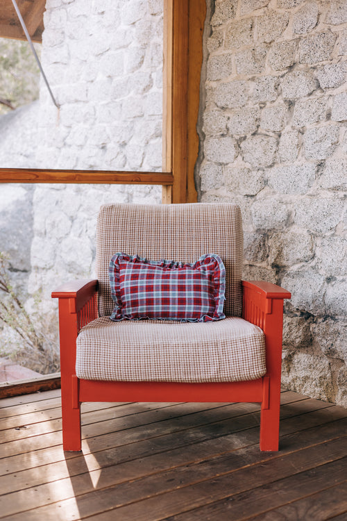 Red armchair with plaid cushion against a stone wall