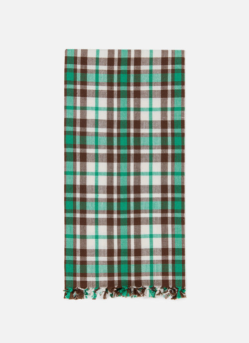 A rectangular plaid tea towel with fringed ends, featuring a pattern of brown, green, and off-white stripes, displayed flat against a light gray background.