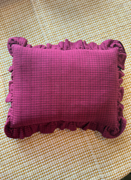 Purple textured pillow with ruffled edges on a checkered fabric background