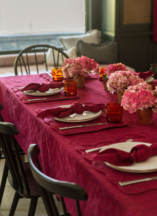 Dining table set with purple tablecloth, napkins, and floral centerpieces.